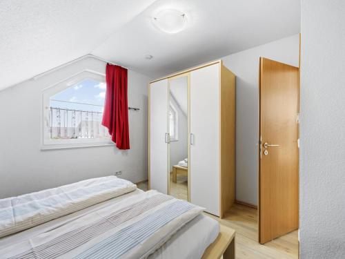 een slaapkamer met een bed en een raam met een rood gordijn bij Stranddistel XL in Boiensdorf