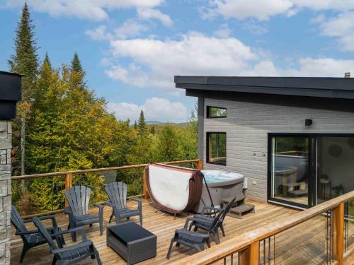 a deck with a tub and chairs and a boat at Maison contemporaine Tremblant- Spa & tranquillité in Lac-Superieur