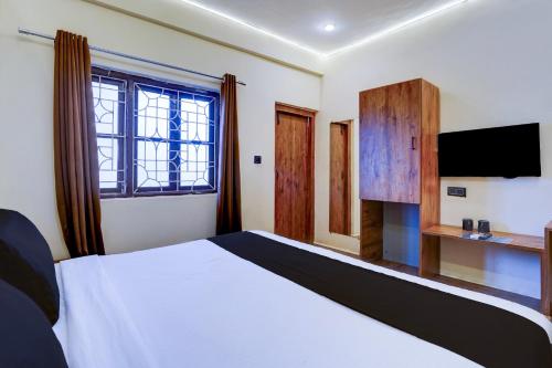 a bedroom with a white bed and a television at Collection O Baga Beach Goa Formerly Traveller Guest House in Baga