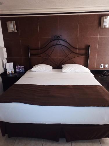 a bedroom with a large bed with a wooden headboard at motel alamo in Guadalajara