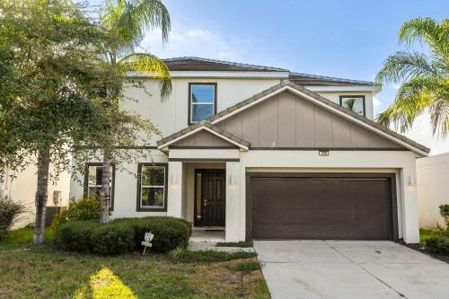 a white house with a garage at Sunny Stay in Orlando - 6BR Home with Pool! in Kissimmee