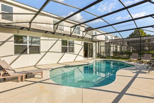 a swimming pool with a glass roof on a house at Sunny Stay in Orlando - 6BR Home with Pool! in Kissimmee