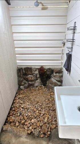 a bathroom with a white sink and a stone wall at Glamping tent in Nelspruit