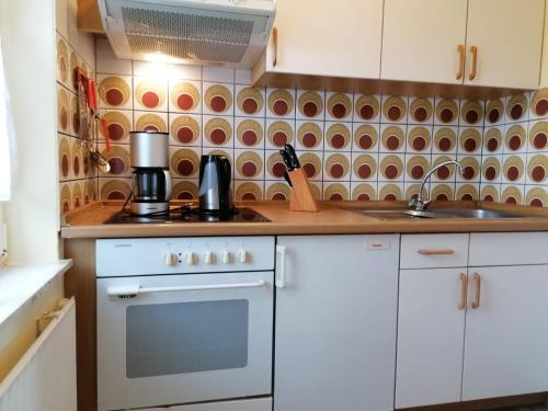 a kitchen with white cabinets and a stove top oven at Hotel Pension garni Haus am Strand in Norddeich