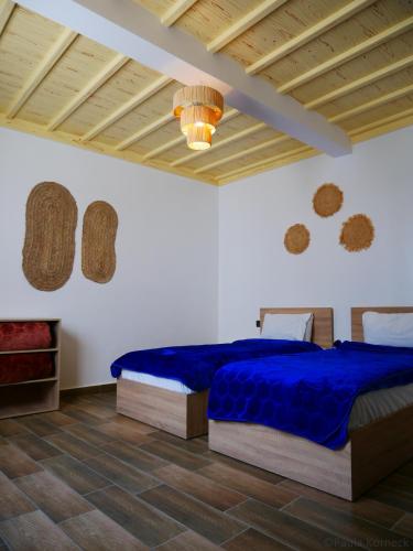 a bedroom with a blue bed and a wooden ceiling at Dar Iziki Separate Apartments in Sidi Kaouki