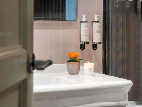 a bathroom sink with a candle and a flower on it at Le Stendhal - Vendôme in Paris