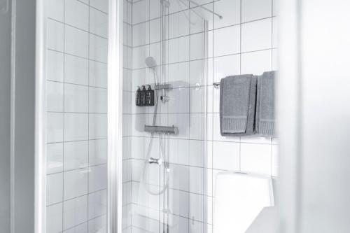 a bathroom with a shower with white tiled walls at Home Hotel Majoren in Skövde