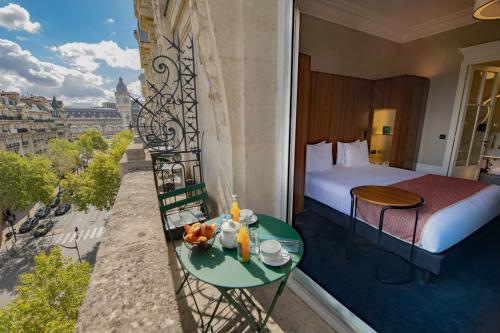 a hotel room with a balcony with a bed and a table at Holiday Inn Paris - Gare de Lyon Bastille by IHG in Paris