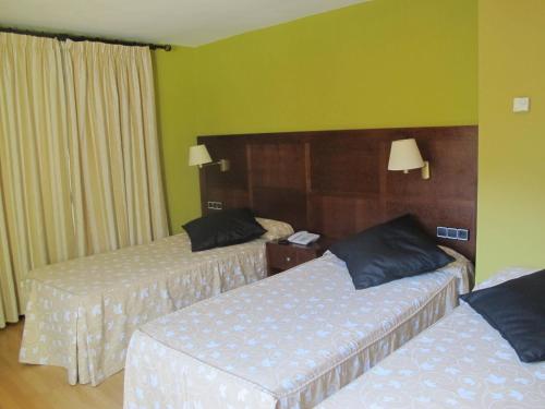 two beds in a hotel room with green walls at Hotel De Rei in Llavorsí