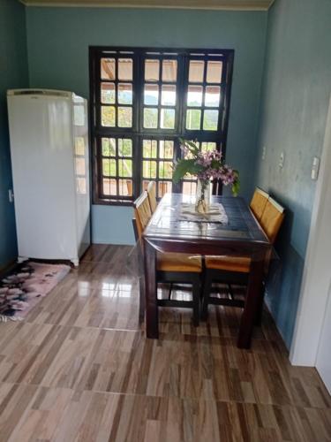 comedor con mesa, sillas y nevera en Cantinho da Ane, en Morro Reuter