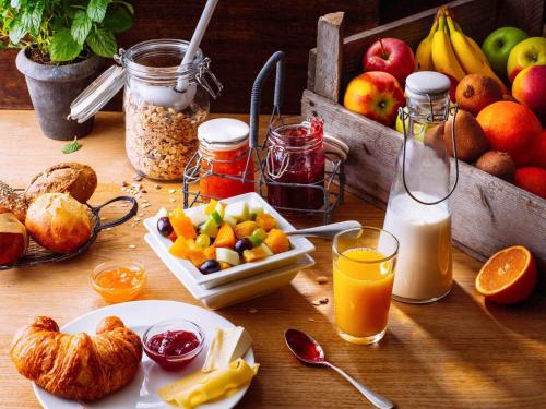 a wooden table with fruits and other foods and drinks at Hotel ibis Porto Sul Europarque in Santa Maria da Feira