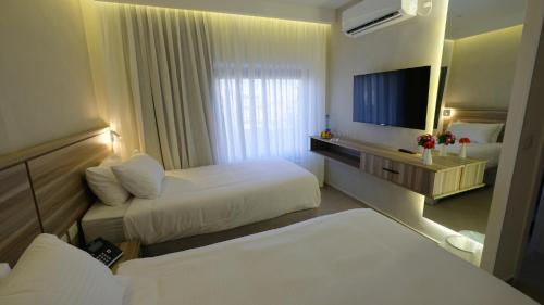 a hotel room with two beds and a flat screen tv at Harmony City Hotel - Jerusalem in Jerusalem