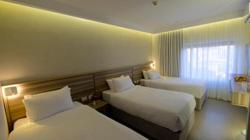 a hotel room with two beds and a window at Harmony City Hotel - Jerusalem in Jerusalem