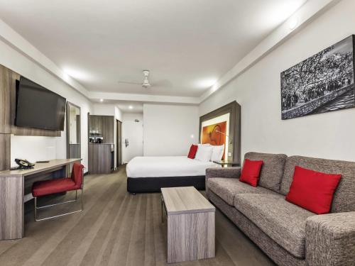 a hotel room with a bed and a couch at Novotel Darwin CBD in Darwin