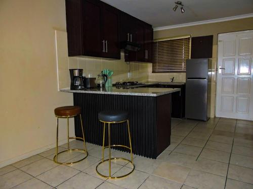 a kitchen with a counter and two stools in it at Poplar place Thornton in Cape Town