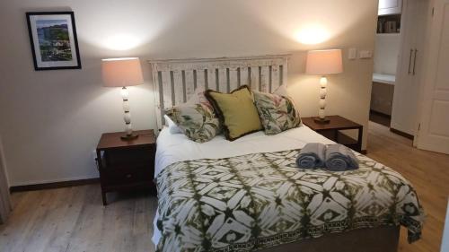 a bedroom with a bed with two lamps and two shoes on it at Dayspring Cottage in Howick