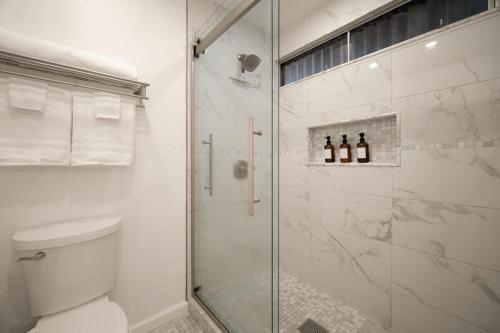 a white bathroom with a shower and a toilet at Modern studio, AC, king bed, private lanai in Princeville