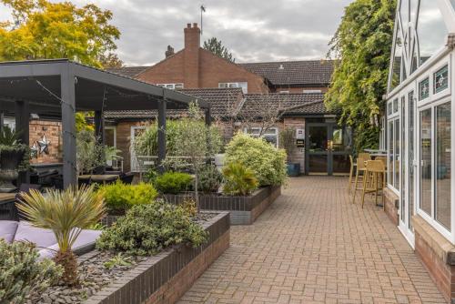 a courtyard with plants and tables and a building at Brackenborough Hotel, BW Signature Collection in Louth