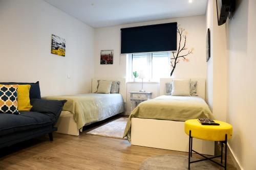 a bedroom with two beds and a couch and a tv at Castelo Terrace Apartement in Leiria