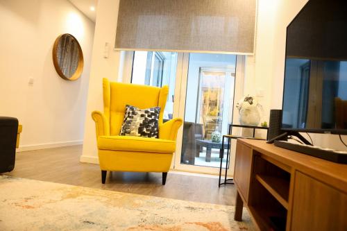 a living room with a yellow chair and a television at Castelo Terrace Apartement in Leiria