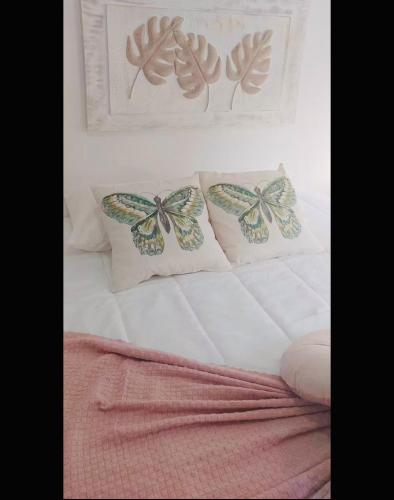 a bed with three pillows with butterflies on it at Casa da Tia Binda - refúgio no centro histórico in Monção