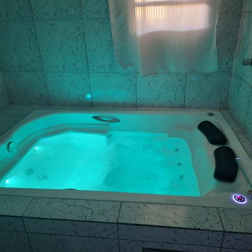 a bath tub with blue water in a bathroom at Pousada da Lorena in Itanhaém