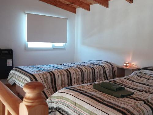 two beds in a room with a window at La Chabela 02 in Trevelín