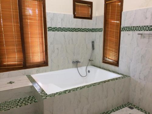 a white bath tub in a bathroom with windows at Lombok Villas, Villa Rembulan in Labuhanpoh