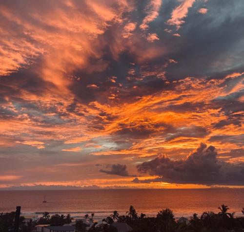 a sunset over the ocean with a beach at Cocon Romantique in Saint-Gilles les Bains