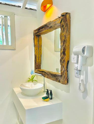 a bathroom with a wooden mirror and a sink at Pousada Tamuré in Caraíva