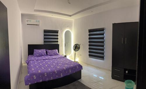 a bedroom with a purple bed with purple pillows at 9th House Apartments in Lagos