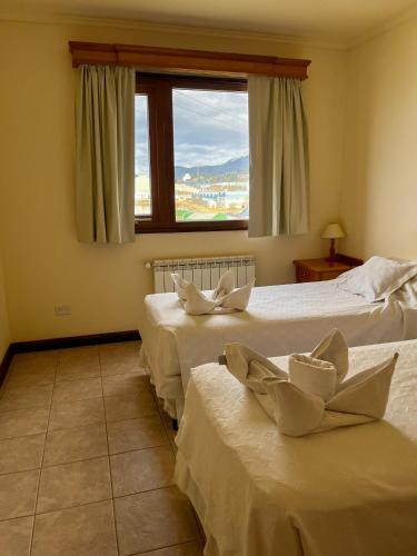 two beds in a room with a window at Balcones del Beagle Apart in Ushuaia
