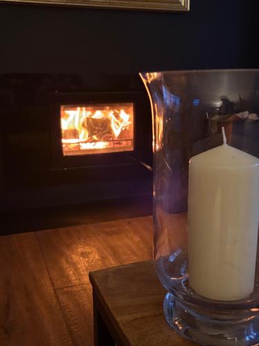 a candle in a glass vase next to a fireplace at Portishead Coastal Retreat in Portishead