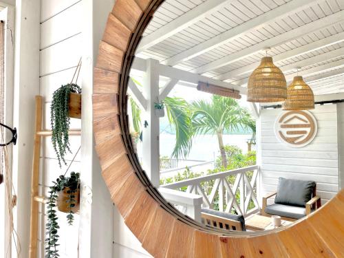 a circular mirror on a porch with a chair and palm trees at La p’tite barque Antillaise in Deshaies