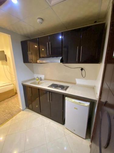 a small kitchen with black cabinets and a sink at فندق الخلفاء الفيصلية الفندقية in Mecca