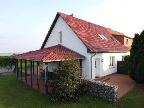 a white house with a red roof and a deck at Kranichhaus Boddenblick in Saal