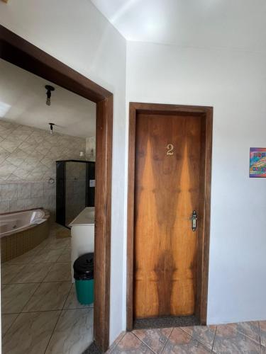 a wooden door in a bathroom with a tub at Espia Mata - Pousada Hostel in Ponta Grossa