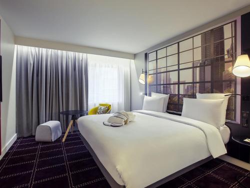 a hotel room with a large white bed and a window at Mercure Paris la Défense Grande Arche in Nanterre