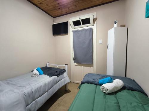 two beds in a room with a window and a refrigerator at Parvis Magna HOSTAL in Barraquero