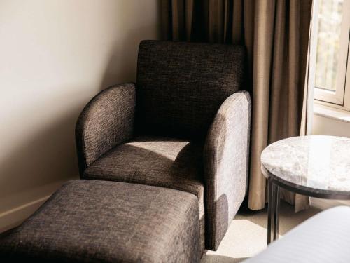 a chair in a room with a table at Mercure Sydney Parramatta in Sydney