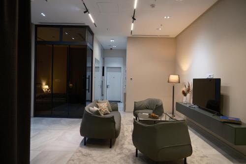 ein Wohnzimmer mit Sofa, Sesseln und Fernseher in der Unterkunft Tashkent City Downtown Deluxe Host Apartments in Taschkent