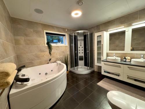 Un baño con bañera y dos lavabos y un inodoro. en Liten leilighet med hage og stort bad, en Malvik