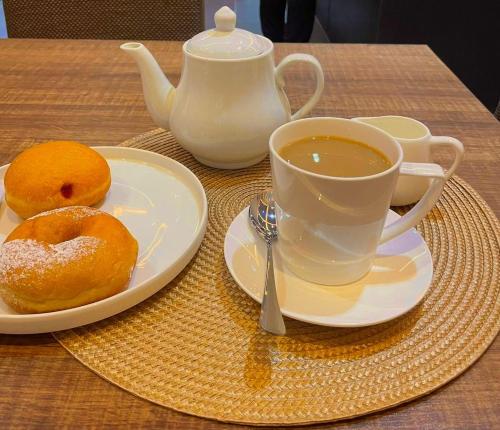 a cup of coffee and two donuts on a table at The Cordis Hotel, Ikeja in Ikeja