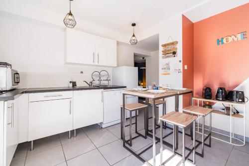 a kitchen with white cabinets and a table with stools at Nid confort proche du canal du midi 2 terrasses Labège in Labège