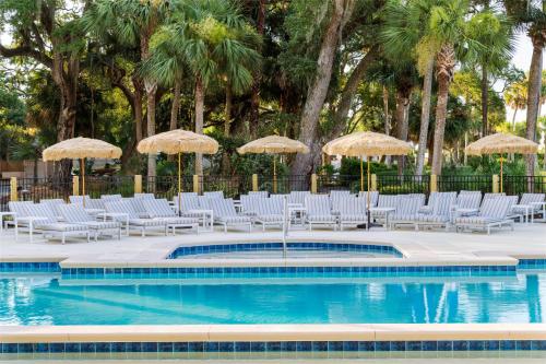 a group of chairs and umbrellas next to a swimming pool at Sonesta Resort Hilton Head Island in Hilton Head Island