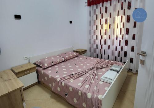 een slaapkamer met een bed met een roze dekbed bij Flor Apartment in Pogradec