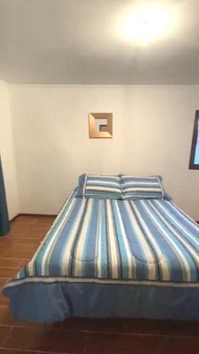 a bed with blue and white striped sheets in a room at Vacation rental house La Serena Chile in La Serena