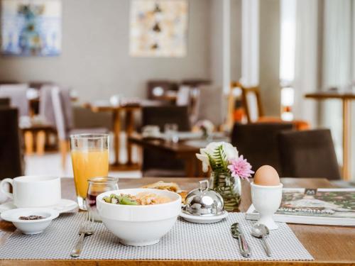 a table with a bowl of food and a glass of orange juice at Le Diwan Hotel Rabat - MGallery Collection in Rabat
