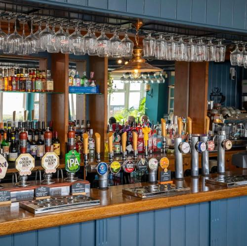 a bar with a lot of bottles of alcohol at Commodore Hotel by Greene King Inns in Bournemouth