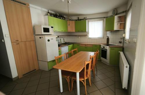 a kitchen with green cabinets and a wooden table and chairs at Magyar Tenger Pihenőház, house for 8 with garden at Balaton in Balatonkenese